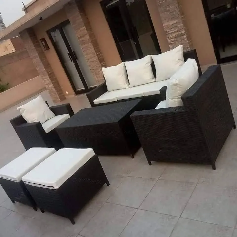 A dark rattan sofa set with cream cushions, from Wasi Craft's listing
