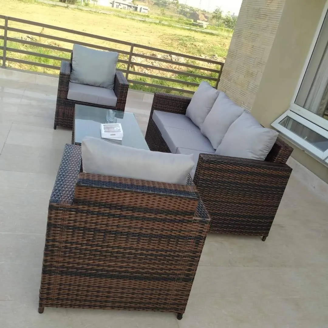 A brown rattan sofa set with grey cushions on a customer's terrace